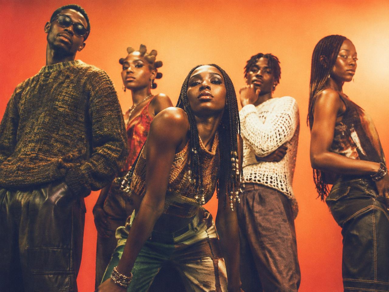 A group of young creatives photographed against an orange backdrop